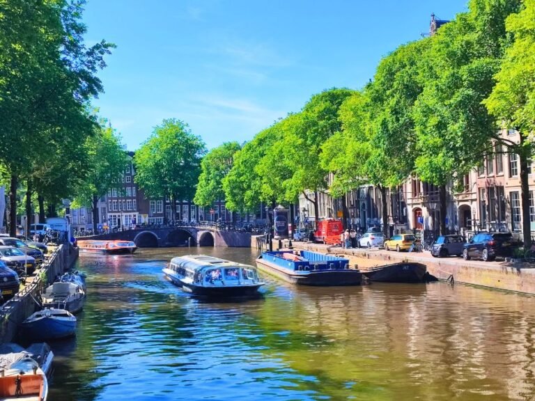 Canal view with tour boats and leafy trees – one of the highlights during the Amsterdam city game