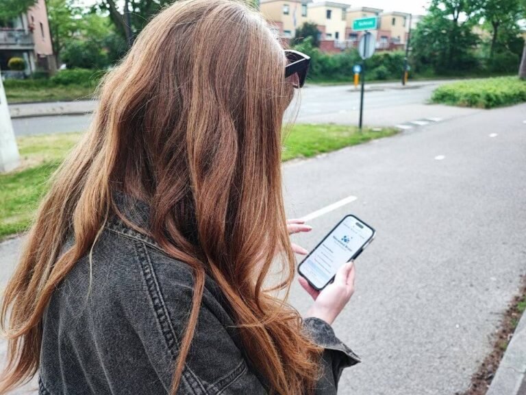 Buurtnetwerker Julia bekijkt een opdracht van Wijkgame Nieuwland op haar telefoon